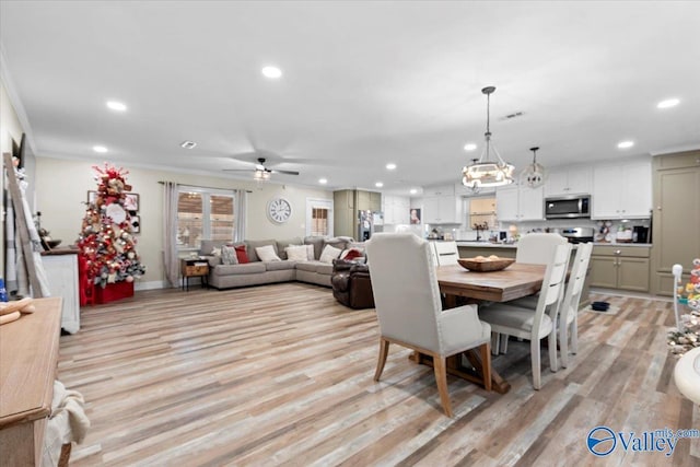 dining space featuring ceiling fan with notable chandelier, light wood-type flooring, and ornamental molding