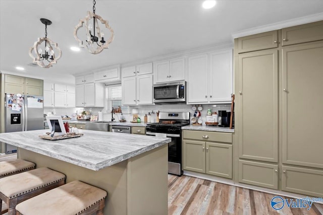 kitchen with stainless steel appliances, a kitchen breakfast bar, decorative light fixtures, a kitchen island, and light wood-type flooring