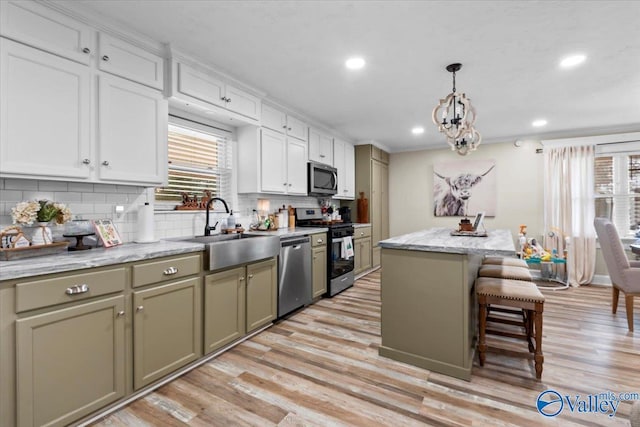 kitchen with tasteful backsplash, stainless steel appliances, sink, light hardwood / wood-style flooring, and a kitchen island