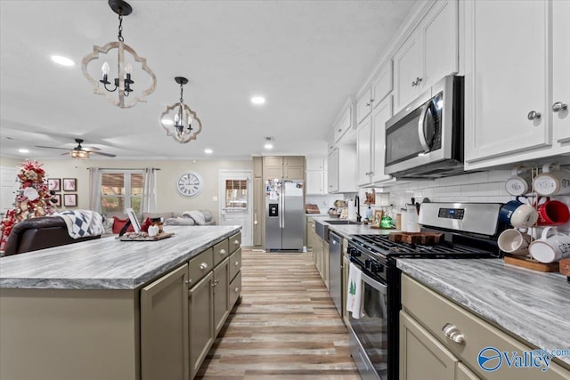 kitchen with a center island, hanging light fixtures, stainless steel appliances, light hardwood / wood-style flooring, and ceiling fan with notable chandelier