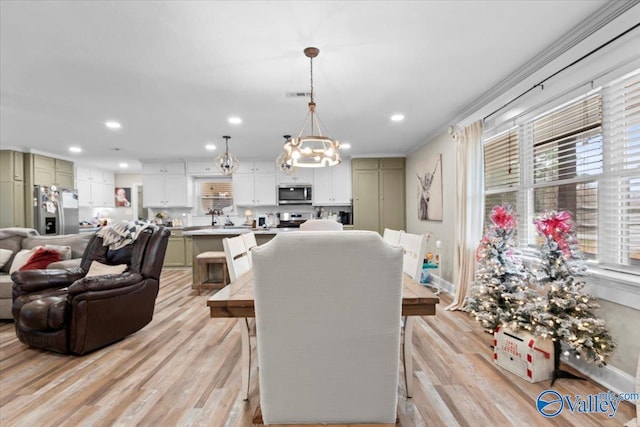 living room with crown molding, light hardwood / wood-style floors, and an inviting chandelier