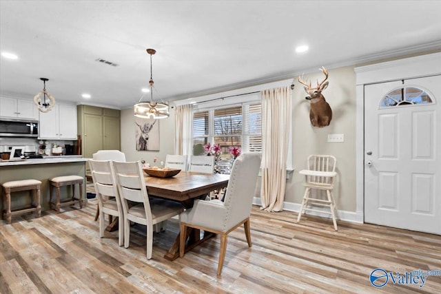 dining area with a chandelier, light hardwood / wood-style flooring, and crown molding