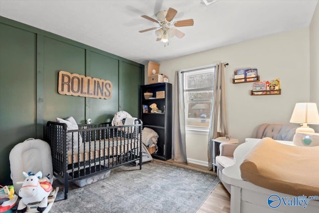 bedroom with ceiling fan, light hardwood / wood-style floors, and a crib