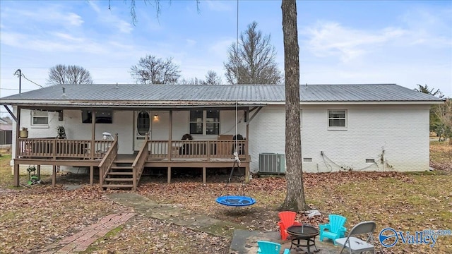 back of property with a fire pit, a deck, and central air condition unit