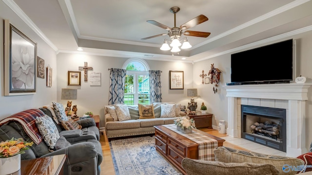 112 Bullard Rd, Hazel Green, AL 35750 - living room featuring a tray ceiling, ceiling fan, a fireplace, ornamental molding, and light wood-style flooring