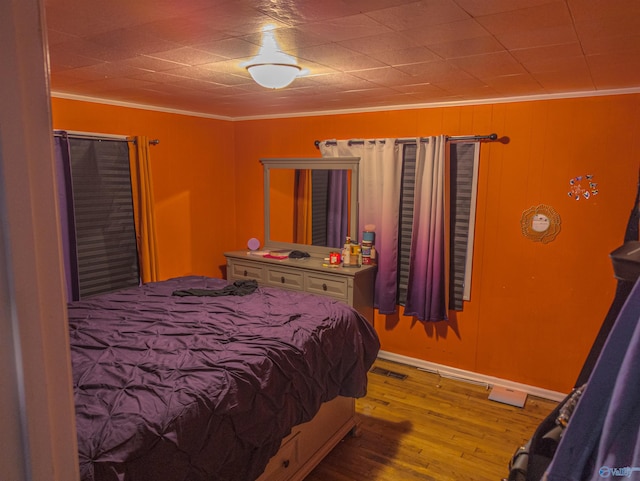 bedroom featuring ornamental molding and light hardwood / wood-style floors