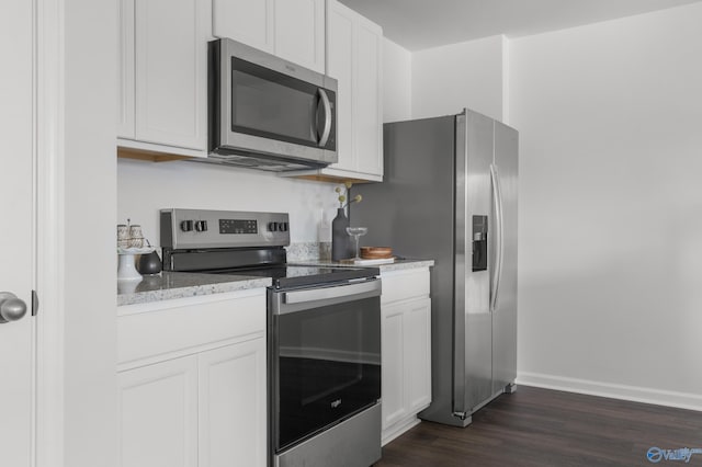 kitchen featuring white cabinets, appliances with stainless steel finishes, light stone countertops, and dark wood-type flooring