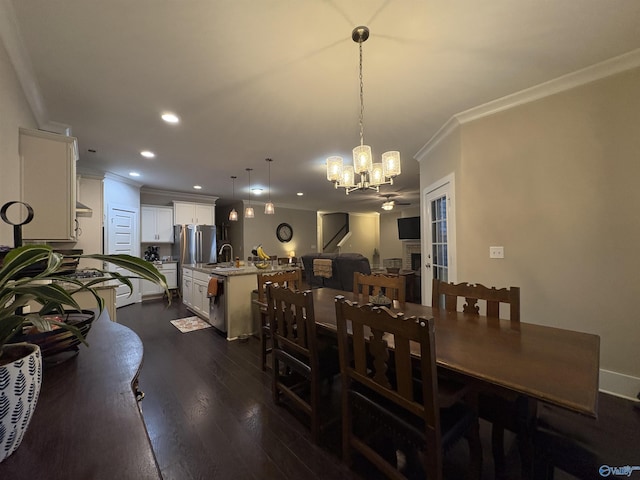 dining space featuring ornamental molding, sink, a notable chandelier, and dark hardwood / wood-style flooring