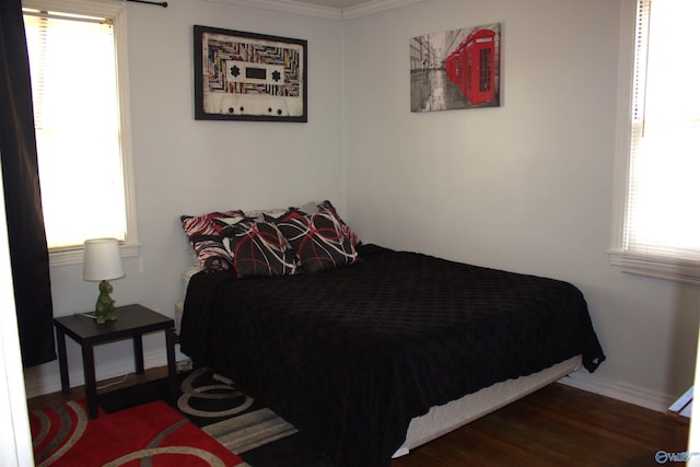 bedroom with dark wood-type flooring, ornamental molding, and multiple windows