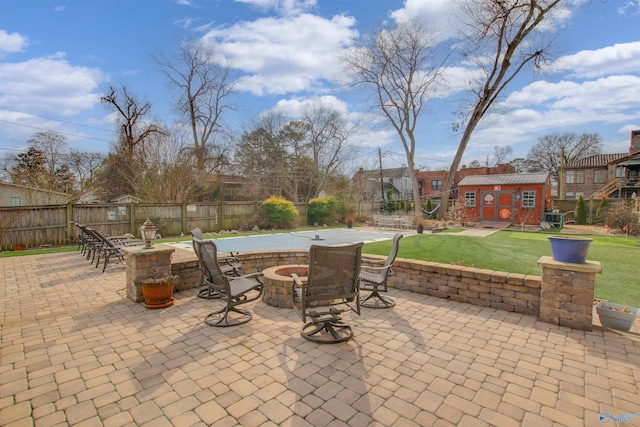 view of patio featuring an outbuilding, a fenced backyard, and a fire pit