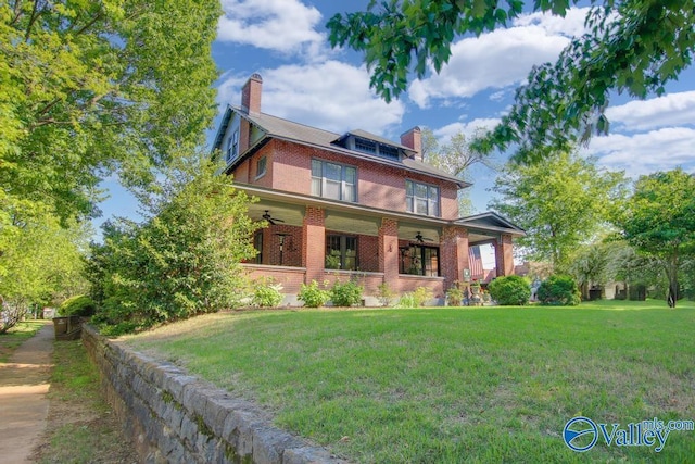 traditional style home with a front yard, brick siding, ceiling fan, and a chimney