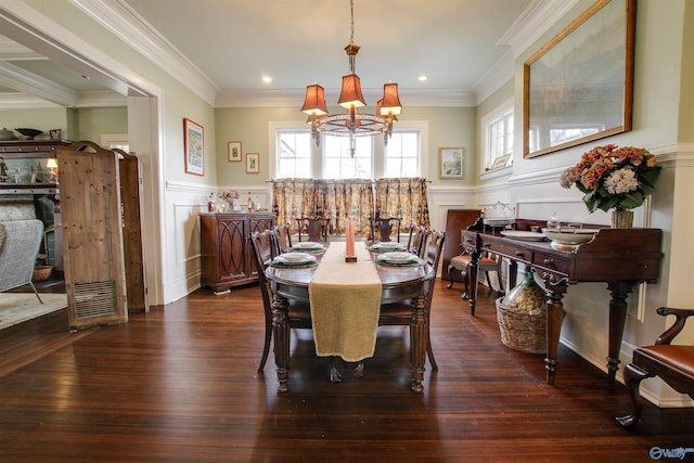 dining room featuring crown molding, dark wood-style flooring, a wainscoted wall, and a notable chandelier