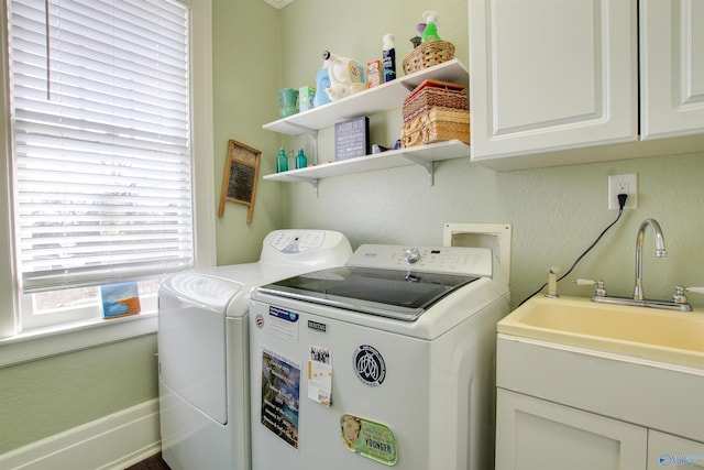 washroom with cabinet space, a sink, and washing machine and clothes dryer