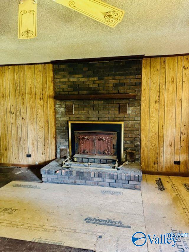 details featuring wooden walls, a brick fireplace, and a textured ceiling