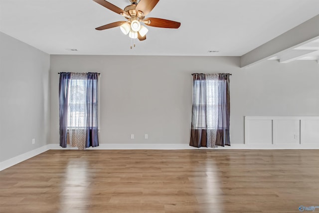 empty room with a ceiling fan, baseboards, visible vents, and light wood finished floors