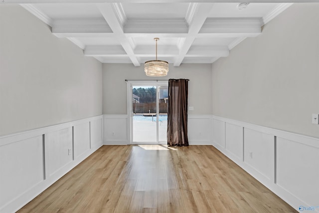 unfurnished dining area with light wood-style floors, coffered ceiling, beam ceiling, and wainscoting