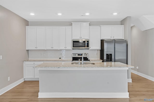 kitchen featuring stainless steel appliances, a sink, a kitchen island with sink, and white cabinetry
