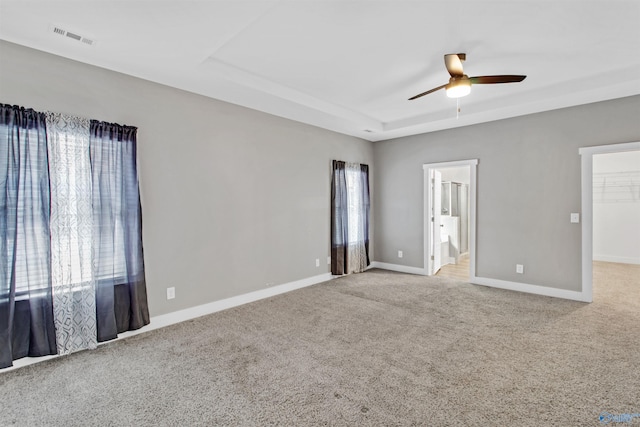 interior space featuring visible vents, baseboards, a spacious closet, a tray ceiling, and carpet