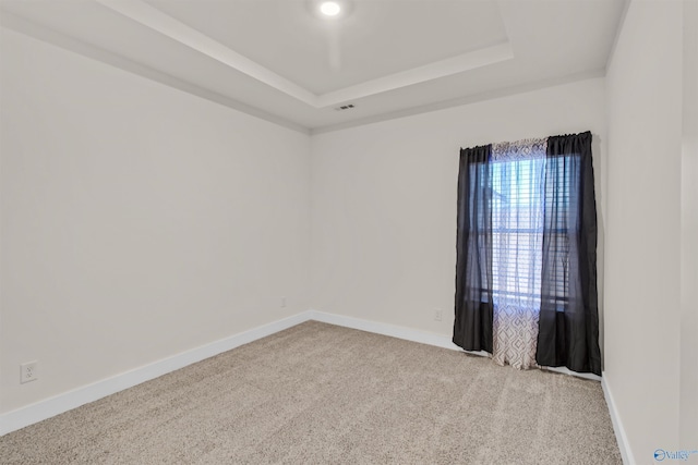 carpeted empty room featuring a raised ceiling, visible vents, and baseboards