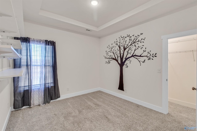 unfurnished room with carpet floors, visible vents, baseboards, and a raised ceiling