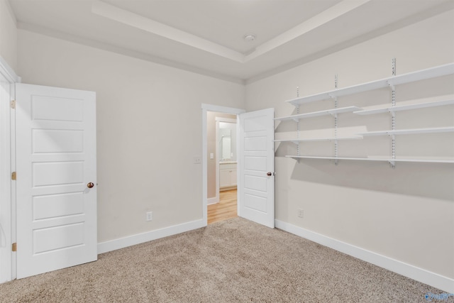 unfurnished bedroom with carpet floors, baseboards, and a tray ceiling