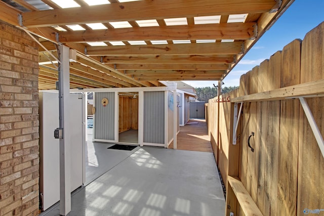 view of patio / terrace with an outdoor structure, fence, and a shed