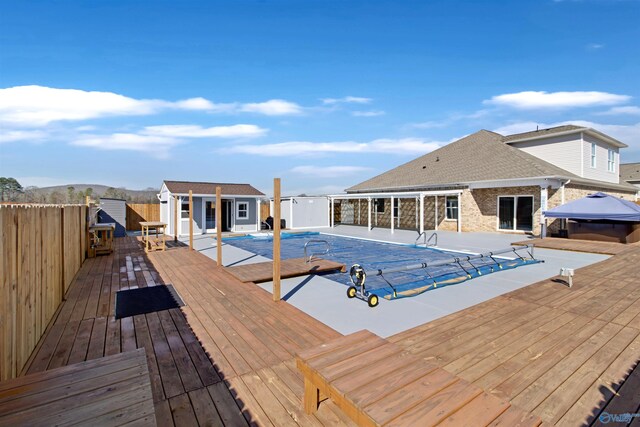view of pool with a deck, a storage structure, an outdoor structure, fence, and a fenced in pool