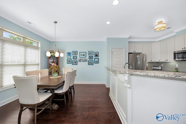 119 Autumn Cove Dr, Madison, AL 35756 - kitchen with appliances with stainless steel finishes, dark wood-style floors, decorative backsplash, ornamental molding, and light stone countertops