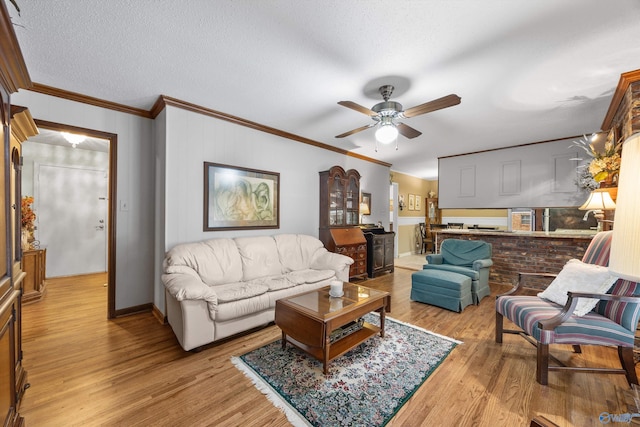 living room featuring ornamental molding, light hardwood / wood-style flooring, a textured ceiling, and ceiling fan