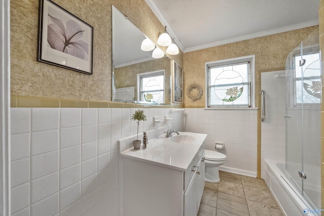 full bathroom featuring vanity, ornamental molding, bath / shower combo with glass door, tile walls, and toilet