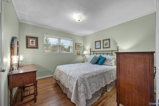 bedroom with crown molding, hardwood / wood-style floors, and a textured ceiling