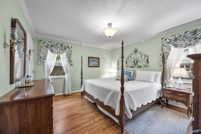 bedroom featuring crown molding, light wood-type flooring, and a textured ceiling