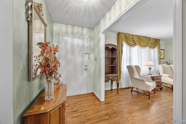 interior space featuring light hardwood / wood-style floors, ornamental molding, and a textured ceiling