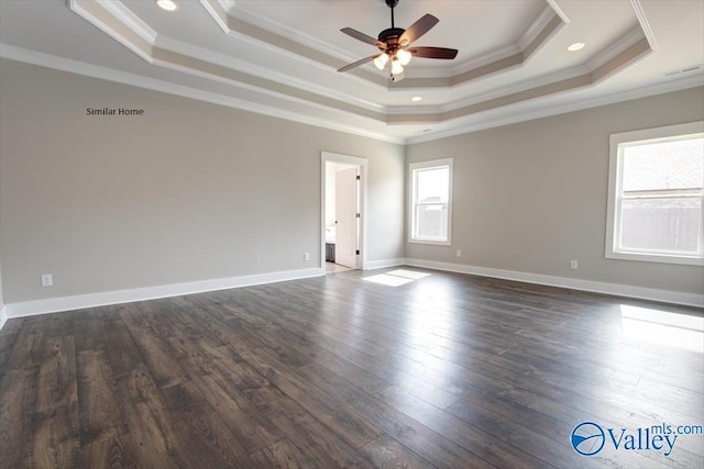 spare room with crown molding, a tray ceiling, and dark wood-type flooring