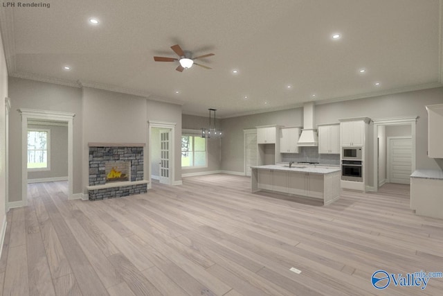 unfurnished living room with ceiling fan, ornamental molding, a stone fireplace, and light wood-type flooring