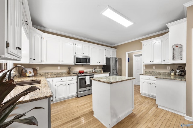 kitchen featuring white cabinetry, sink, a center island, light stone countertops, and appliances with stainless steel finishes