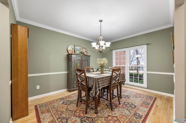 dining area featuring a notable chandelier, light hardwood / wood-style floors, and crown molding