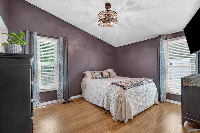 bedroom with a notable chandelier, baseboards, vaulted ceiling, and light wood finished floors