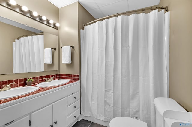 bathroom with double vanity, a sink, decorative backsplash, and toilet