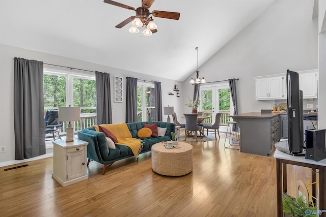 living area with high vaulted ceiling, visible vents, ceiling fan with notable chandelier, and light wood-type flooring