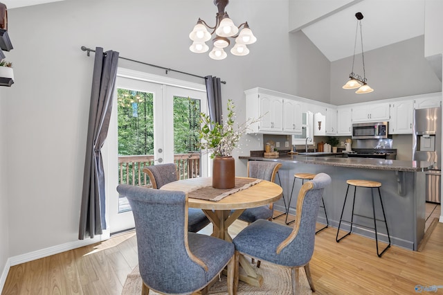 dining area featuring french doors, high vaulted ceiling, baseboards, a notable chandelier, and light wood-style floors