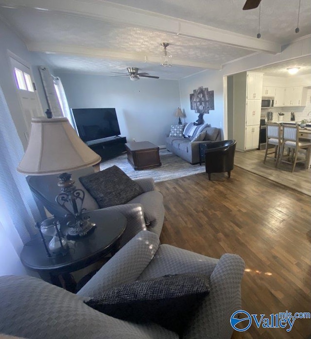 living room with ceiling fan, hardwood / wood-style floors, and beamed ceiling