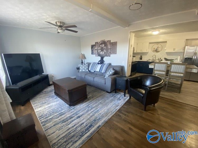 living room with a textured ceiling, ceiling fan, beam ceiling, and dark hardwood / wood-style floors