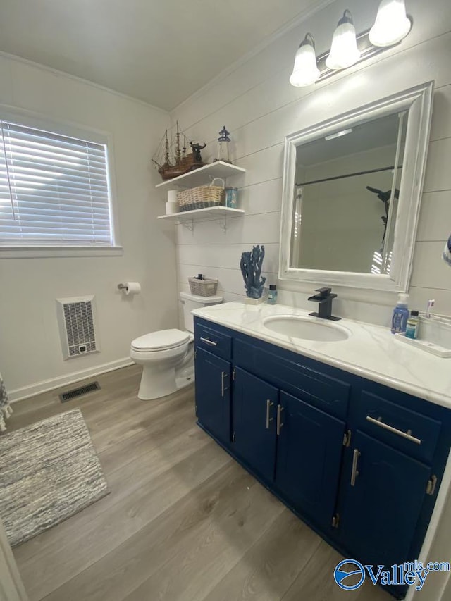 bathroom with toilet, wood-type flooring, walk in shower, ornamental molding, and vanity