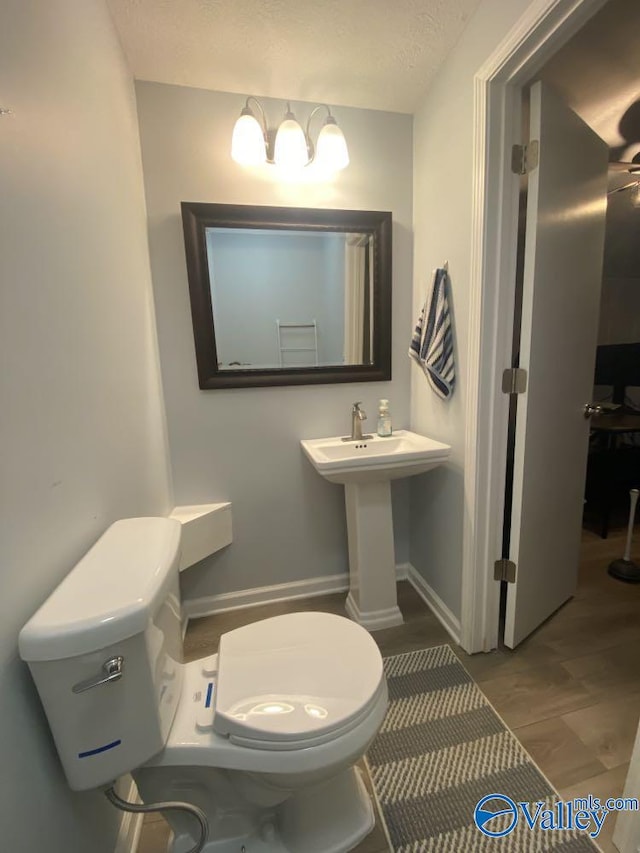 bathroom with toilet, wood-type flooring, and a textured ceiling