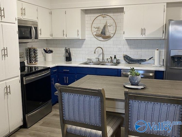 kitchen featuring white cabinetry, appliances with stainless steel finishes, blue cabinetry, and sink