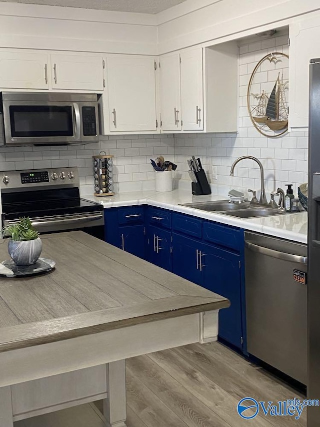 kitchen with white cabinets, appliances with stainless steel finishes, sink, and blue cabinetry