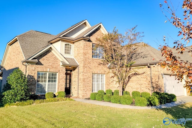 view of front of home with brick siding, roof with shingles, an attached garage, and a front yard