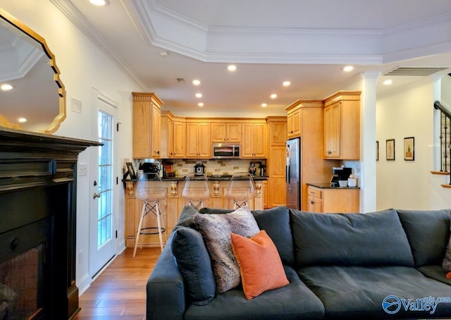 living area featuring a tray ceiling, crown molding, a fireplace, recessed lighting, and wood finished floors