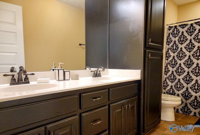 bathroom featuring tile patterned floors, a sink, toilet, and double vanity